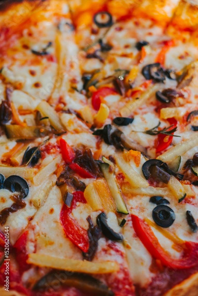 Fototapeta Pizza topping with vegetables and olives close-up. Appetizing pizza with cheese. Eating pattern view from above. Concept of delicious pizza and delivery of Italian cuisine