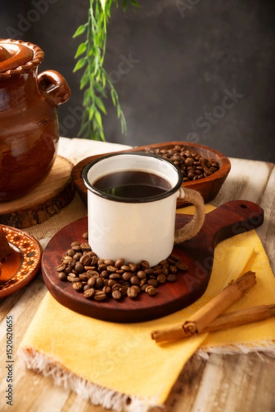 Fototapeta Cafe de Olla. Traditional Mexican coffee and basic ingredients for its preparation, coffee, cinnamon and piloncillo, served in a metallic cup called "peltre" on a rustic wooden surface.