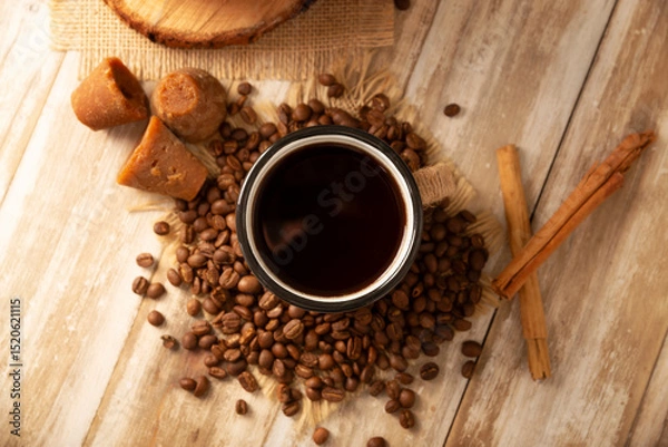 Fototapeta Cafe de Olla. Traditional Mexican coffee and basic ingredients for its preparation, coffee, cinnamon and piloncillo, served in a metallic cup called "peltre" on a rustic wooden surface.