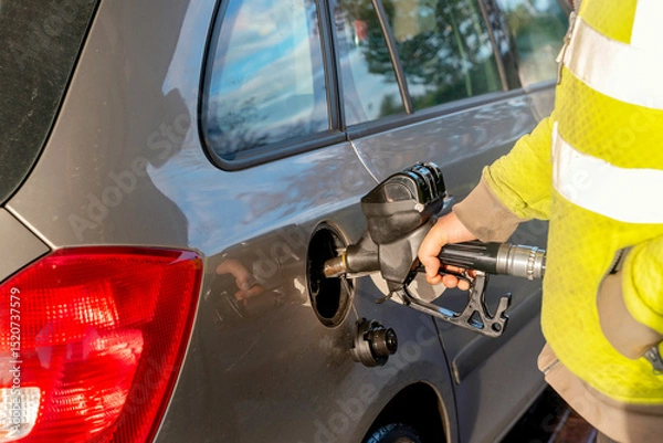 Obraz Driver fills the gas tank of a car at gas petrol station as essential task of the travel routine, ensuring the car is ready for the day's commuting needs