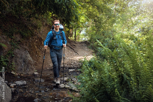 Fototapeta Hiker with backpack walking along forest trail through mountain stream.