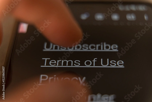 Fototapeta Finger tapping on a smartphone screen with visible Terms of Use links in dark mode.