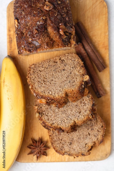 Fototapeta Vegan whole wheat banana bread with cinnamon on wooden board, top view
