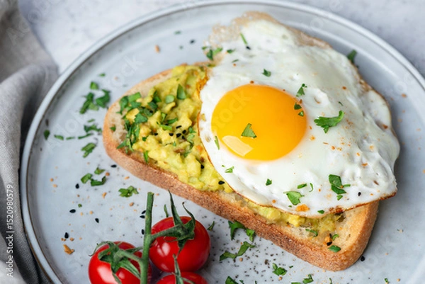Fototapeta Toasted bread with mashed avocado and fried egg. Breakfast or brunch in cafe