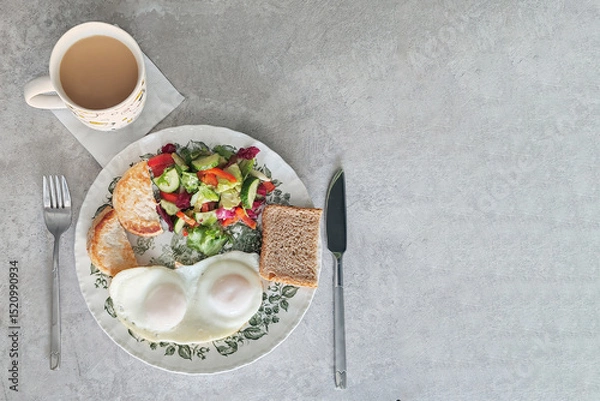 Obraz Delicious breakfast plate featuring sunny-side-up eggs, fresh vegetable salad, toast, and a steaming cup of coffee arranged on a table set for a perfect morning meal