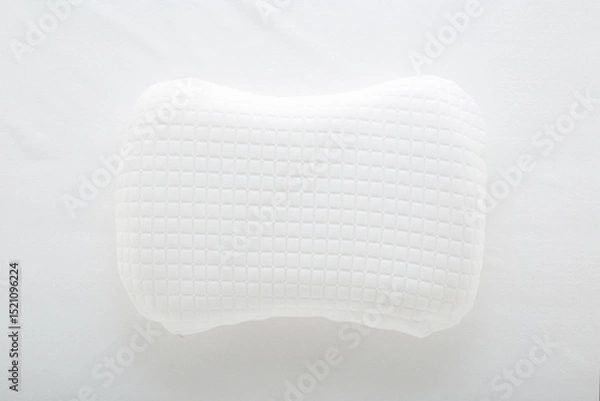 Fototapeta New soft memory foam pillow with white cover on mattress background. Closeup. Top down view.