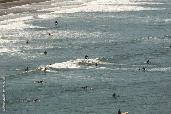 Fototapeta Surfers Wait for and Catch Waves