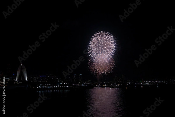 Fototapeta Fireworks explode in the sky over Yokohama Port, with the city skyline in the background