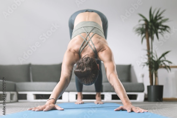 Obraz Woman practicing downward-facing dog yoga pose in modern living room setting