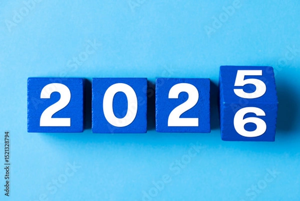 Fototapeta 2026 Happy New Year. Wooden cube block change from 2025 to 2026 on blue. Concept 2026 New Year background. Business, resolutions, goals, inspiration, success, ideas