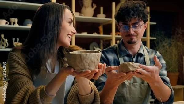 Fototapeta Caucasian woman man teacher student potter artist teaching sculpture ceramics clay process modeling at pottery workshop couple date girl guy creating crockery handmade eco craft studying in art studio