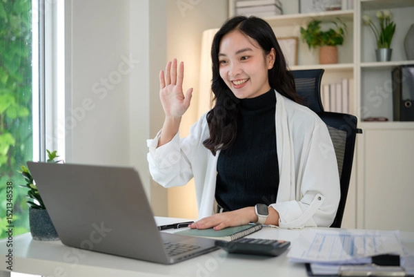 Obraz Friendly businesswoman ttending a virtual meeting, greeting colleagues with a cheerful expression.