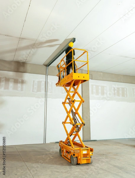Fototapeta Construction worker using scissor lift to install ceiling beams in warehouse