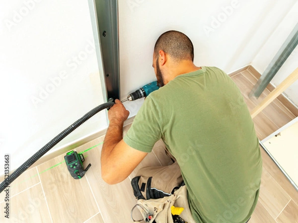 Fototapeta Electrician installing corrugated pipe for electrical wiring in plasterboard wall