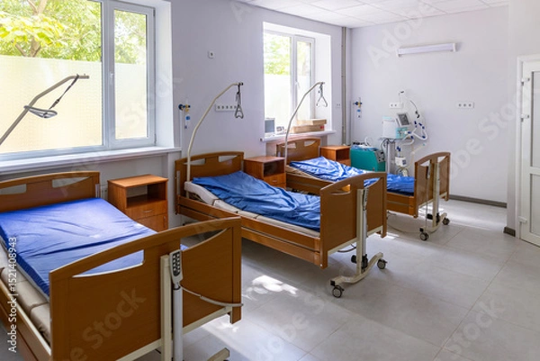 Fototapeta A multi-bed hospital ward features three empty beds, each with a lung ventilator, oxygen concentrator, and oxygen hub, in a brightly lit, sterile environment.