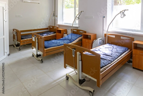 Fototapeta A multi-bed hospital ward features three empty beds, each with a lung ventilator, oxygen concentrator, and oxygen hub, in a brightly lit, sterile environment.
