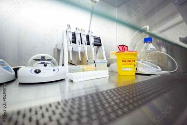 Fototapeta Equipment for DNA/RNA extraction, including pipettes and a shaker, is inside a ventilated safety cabinet in a laboratory