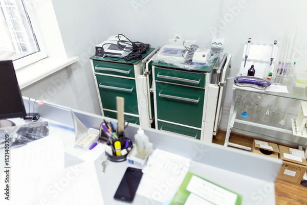 Fototapeta Two medical carts with green drawers hold laboratory equipment, test tube racks, and various medical supplies in a clean clinic room