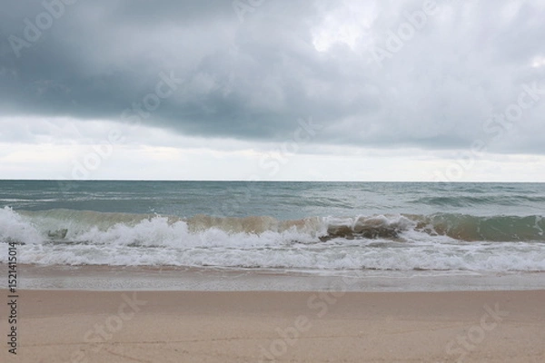 Obraz Big waves crashing against the beach with great force, splashing water. A view of the sea with strong waves on a sunless evening and a gloomy sky. The atmosphere looks like it's going to rain.
