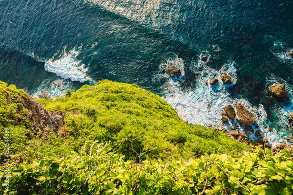 Fototapeta Ocean with waves crashing on rocks stones, view from high rocky coastline