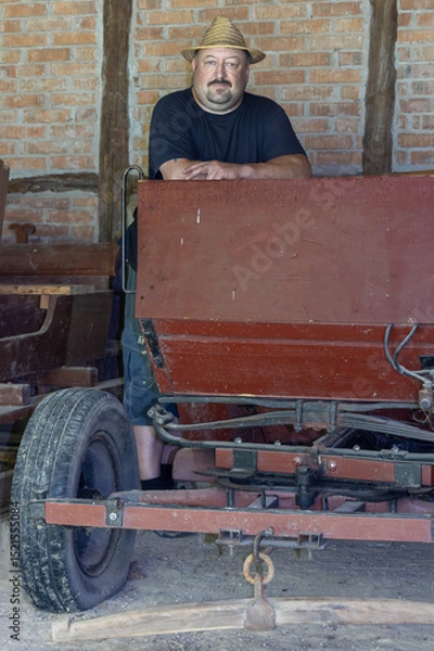 Obraz Farmer standing in barn near old vehicles