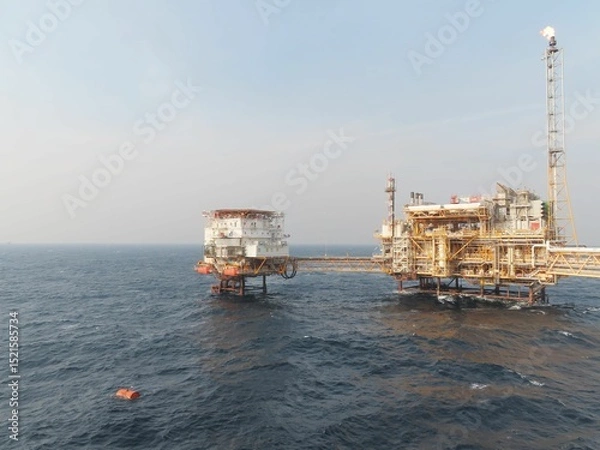 Obraz Oceanic Oil Rig A colossal offshore structure dominates the vast expanse of the sea, a testament to human engineering amidst the powerful waves and clear sky.