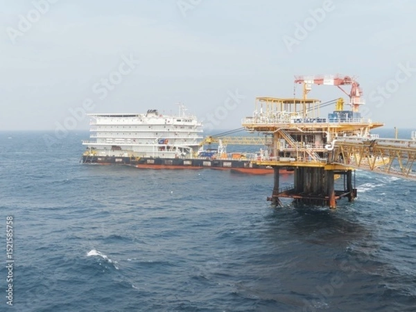 Obraz Offshore oil platform and support vessel navigate rough seas. A glimpse into the energy industrys complex operations at sea, showcasing the scale and challenges of offshore energy production.