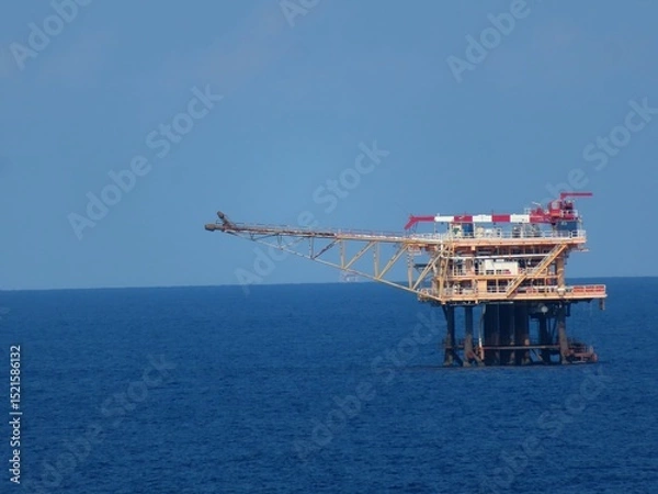Obraz Offshore Oil Platform on a Calm Ocean Under a Clear Blue Sky. A solitary structure against the vastness of the sea, symbolizing industry and exploration.