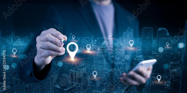 Fototapeta Businessman using mobile phone and stylus for smart city location mapping. Digital location pins and cityscape for modern navigation technology and data connectivity.