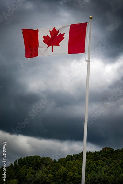 Fototapeta Canada flag flying against dark and moody sky