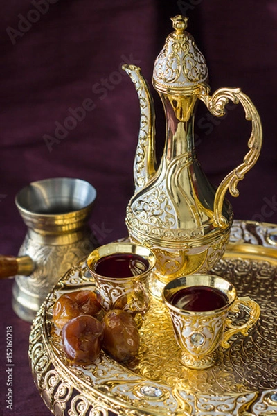Obraz Traditional golden Arabic coffee set with dallah, coffee pot and dates. Dark background. Vertical photo
