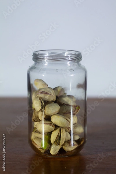 Fototapeta Glass Jar Filled with Pistachio Nuts on Wooden Surface
