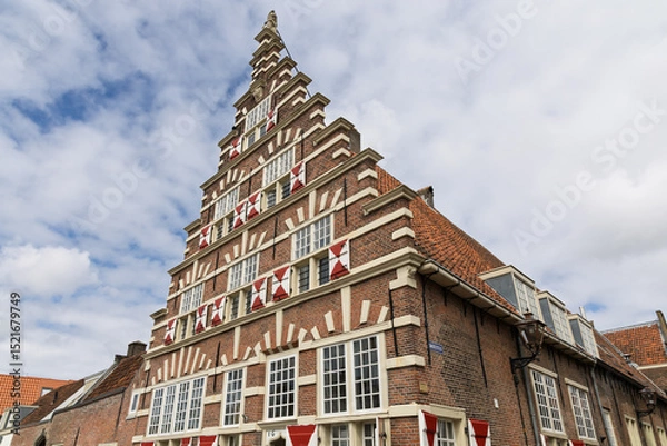 Obraz Dutch architectural gem with a distinct stepped gable, showcasing traditional brickwork and red and white shutters against a bright sky. A historical building in Leiden reflecting European heritage.