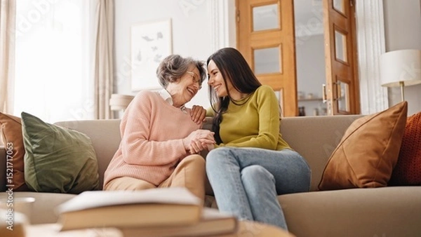 Fototapeta Warm moment of happy Caucasian family hugging each other. Beautiful girl embracing her mature mother while sitting together on sofa. Loving relatives happy about pleasant meeting at home. Relatives.