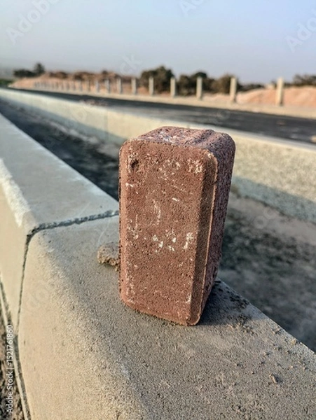 Fototapeta Close-up of brick on concrete barrier along a road