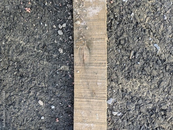 Fototapeta Wooden board on a gravel surface depicting rustic construction elements