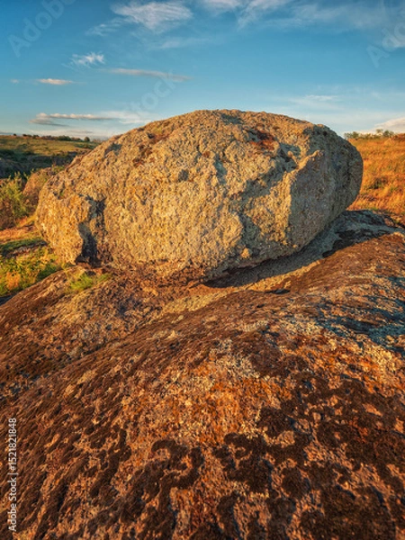 Obraz portrait view to alone granite boulder in sunset light under blue sky