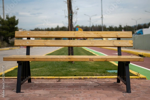 Fototapeta Profile view photo of a wooden bench in the park with nobody in it.