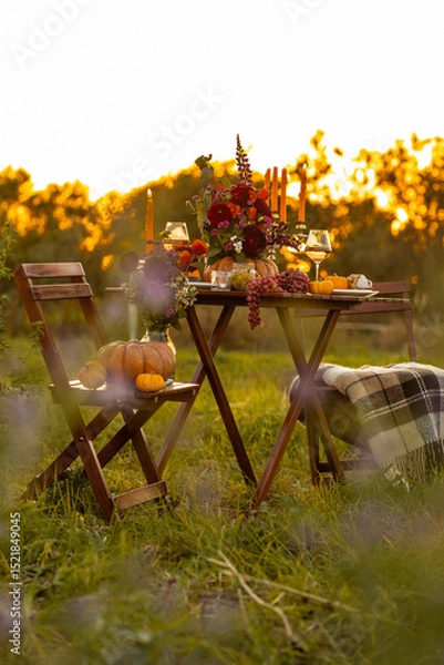 Obraz Hello autumn copy space mock up. Garden romantic party outside with wine, cheese, fruits. Field or meadow, family event, cozy atmosphere, fall vibes. Wooden furniture, pumpkin with flowers centrepiece