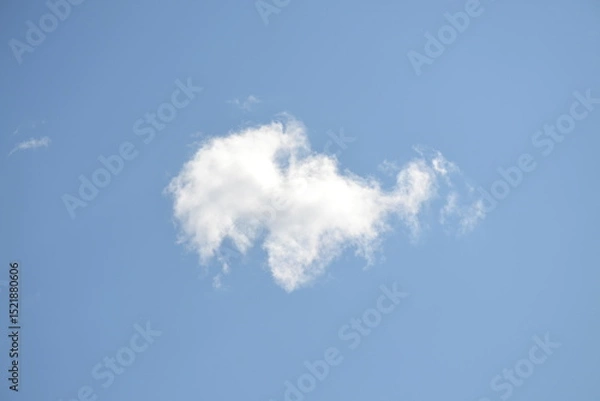 Fototapeta Lonely cloud. A white cloud of a bizarre shape hangs in the light blue clear sky. The cloud is illuminated by the rays of the summer sun. Looking at it, you can understand what it looks like.
