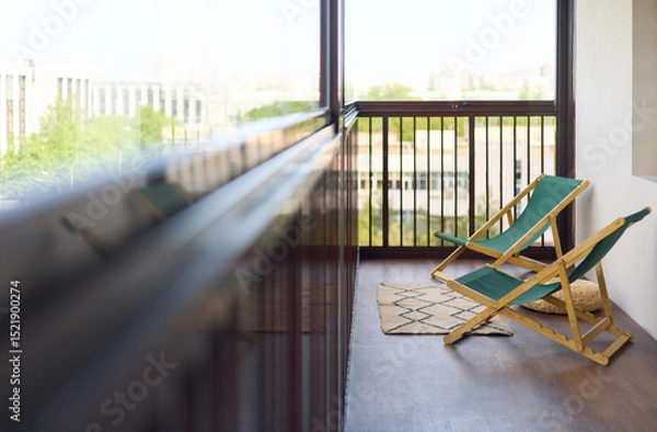 Fototapeta spacious and bright balcony with upholstered chairs, stylish and modern glazing, clear sunny weather