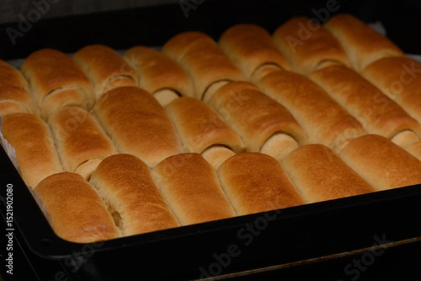 Obraz Golden homemade Parker House rolls baking in the oven. Soft, buttery, and freshly risen buns in a warm kitchen setting.