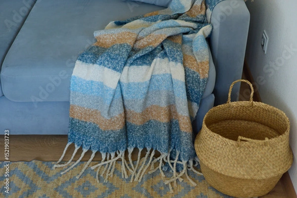 Fototapeta a cozy living room with a blue sofa, a warm blanket on the sofa, a basket for toys and books