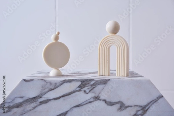 Fototapeta Minimalist abstract geometric sculptures consisting of stacked round and semi-circular shapes displayed on a marble surface against a plain light background
