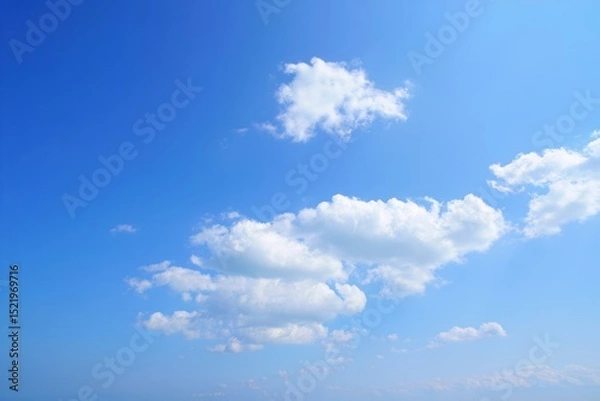 Fototapeta Bright blue sky with scattered white fluffy clouds on a clear sunny day conveying calm and peaceful atmosphere