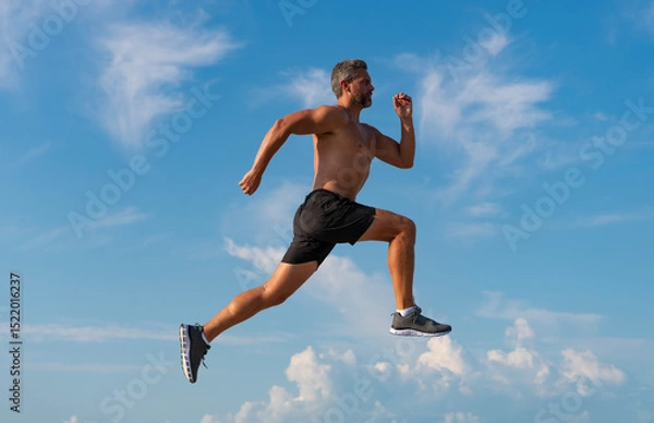 Obraz Runner man bare torso running. Sport and health. Man running against blue sky. Healthy lifestyle. Sportsman running in summer. Sport runner do workout. Sport lifestyle with morning run