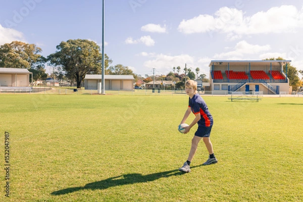 Fototapeta Junior rugby union player practicing ball passes on field