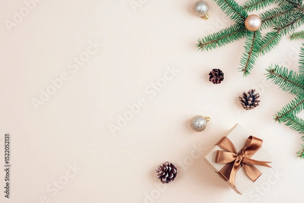 Fototapeta Christmas gift with brown ribbon and decorations on beige background. Top view, flat lay, copy space