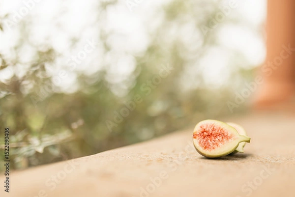 Fototapeta Fresh fig fruit cut in half in natural garden setting with copy space