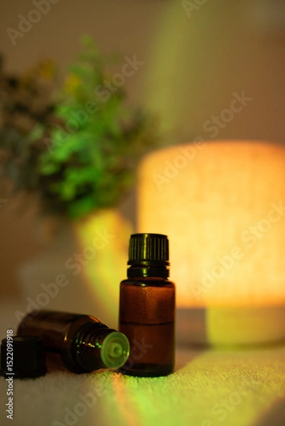 Fototapeta Essential oil diffuser in minimalist space with amber bottles and light causing rainbow effect